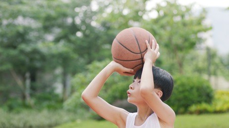 teenage asian boy playing basketball outdoors preparing for shooting