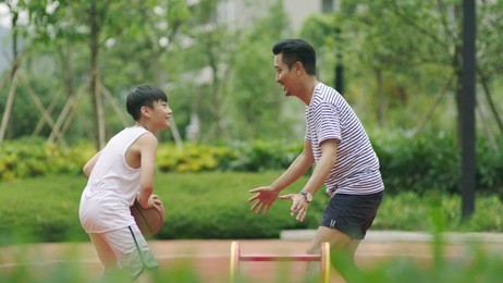 asian father & son playing basketball in garden in morning