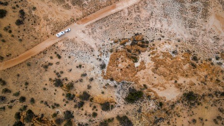 aerial veiw of four wheel drive vehicle and large caravan on an outback road in australia.