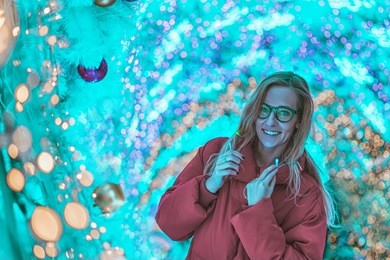 portrait of happy beautiful woman in winter clothes with blured lights on background. cold colored toned.