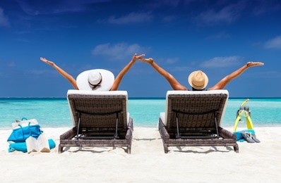 happy couple in sunbeds enjoys their vacation on a tropical beach with turquoise waters