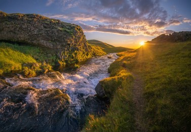 river flowing towards sunset, turning into seljalandsfoss waterfall at the edge of the cliff, iceland