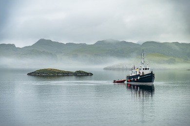 alone boat driving through in the foggy sea in the highlands of scotland