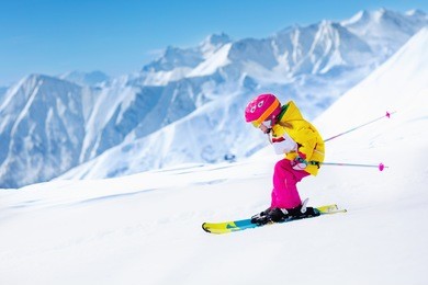 child skiing in mountains. active toddler kid with safety helmet, goggles and poles. ski race for young children. winter sport for family. kids ski lesson in alpine school. little skier racing in snow