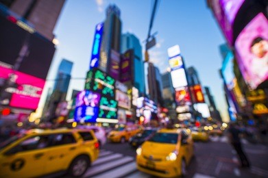 abstract defocus view of new york yellow taxi traffic driving under the colourful neon lights of times square at night in nyc
