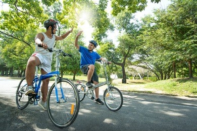 asian teenage boys on bicycles clapping their hands after finishing race. friendship and togetherness concept