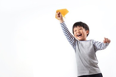 cute asian boy playing with paper plane, isolated on white background.