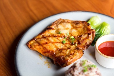 close-up spicy chicken steak with rice in white plate on wooden