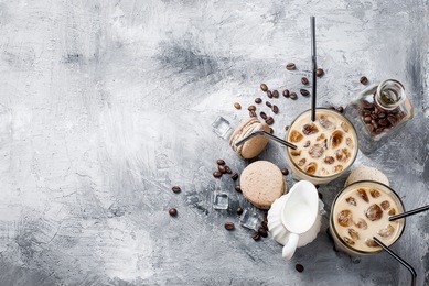 coffee ice in glass, macaroons,, pieces of chocolate and coffee beans  on a gray  table , top view, copy space