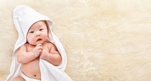 chinese baby boy covered with white blanket on fur bed