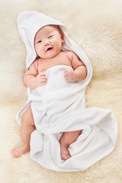 chinese baby boy covered with white blanket on fur bed