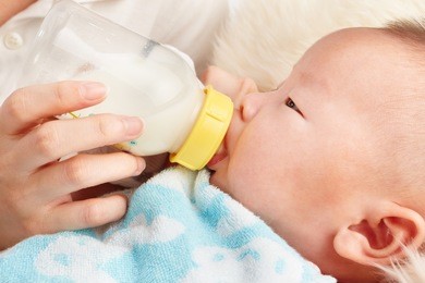 baby is feeding milk from baby's bottle