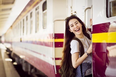 young asian woman student is hanging and smiling at platform train station. teenage travel summer concept.