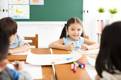 happy little girl drawing in the classroom