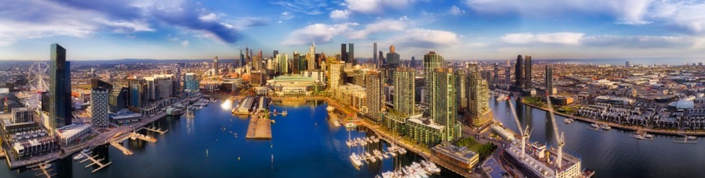 wide panorama of docklands modern suburb in melbourne on yarra river from amusement wheel to city cbd waterfront and port melbourne - elevated aerial view.