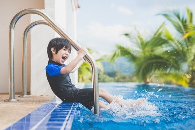 asian child splashing around in the pool