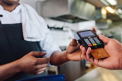 hands of customer paying restaurant bill using credit card. customer making payment through credit card at counter in a restaurant.