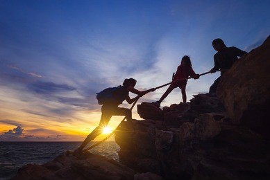silhouette of hikers climbing up on the mountain,team work and helping concept.