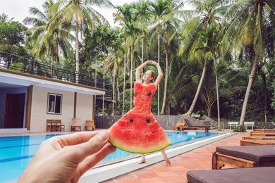 young woman in a watermelon dress on a pool background. the concept of summer, diet and healthy eating.