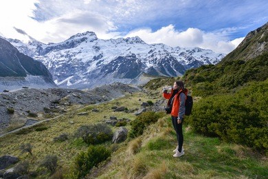 woman backpacker is drinking water on the way mt cook in new zealand
