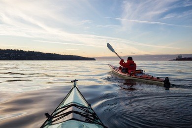 adventure man on a sea kayak is kayaking during a vibrant and colorful winter sunset. taken in vancouver, british columbia, canada. adventure, vacation concept