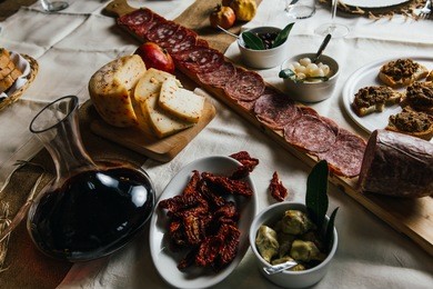 italian tuscan wooden table full of typical dishes, salami, cheese, vegetables and red chianti wine in a classy and stylish environment 