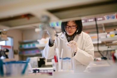 asian scientist pipetting at a biomedical laboratory