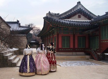 girls in traditional korean dress walking through a courtyard at changdeokgung palace in seoul, south korea