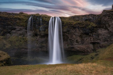 lenticular clouds during a sunrise at seljalandsfoss waterfall in iceland 