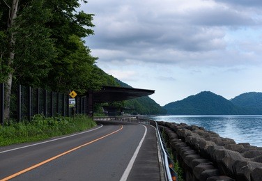 scenic road bending around the beautiful clear mountain lakes of shikotsu-toya national park, hokkaido, japan
