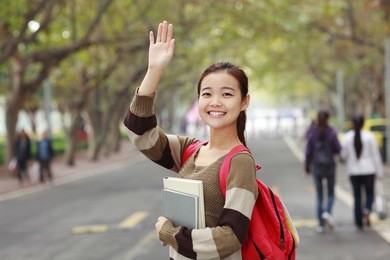 pretty asian college student holding book smile at camera in campus
