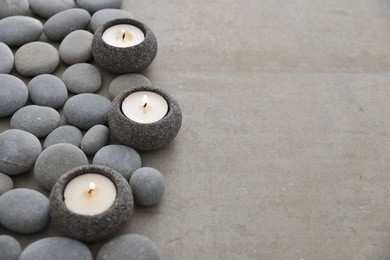 three candle with pile of gray stones on gray background
