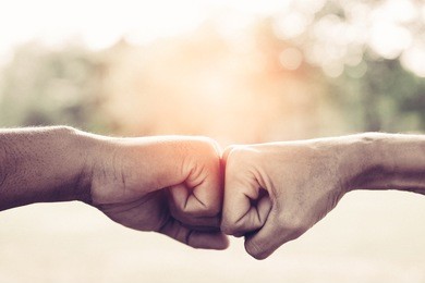 a close up image of a fist bump in vintage tone. hands of young people show strength teamwork in the nature, team concept.