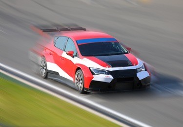race car racing at high speed on speed track with motion blur at sunny day on a racing track