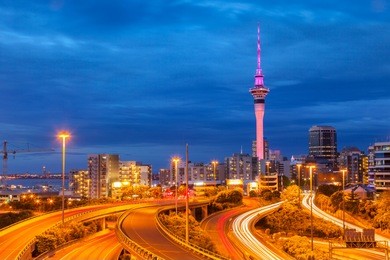 auckland motorway and auckland skyline, illuminated at twilight and with car headlight trails.