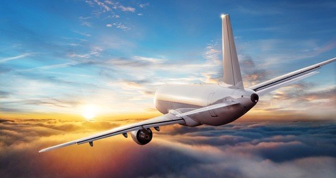 commercial airplane jetliner flying above clouds in beautiful sunset light. travel and business concept. backside view