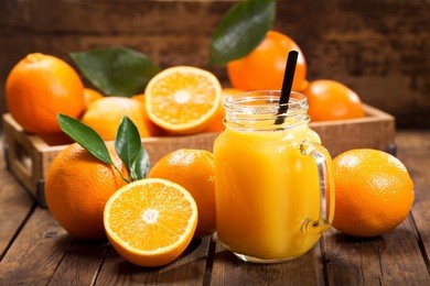 glass jar of fresh orange juice with fresh fruits on wooden table