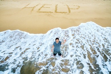 man stands in the water and calls for help on the beach of uninhabited island. inscription help on sand. concept of uninhabited island and castaway. lost in the sea and survivors on the island people.