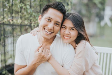happy asian couple in love smiling and having fun while hugging outdoor.