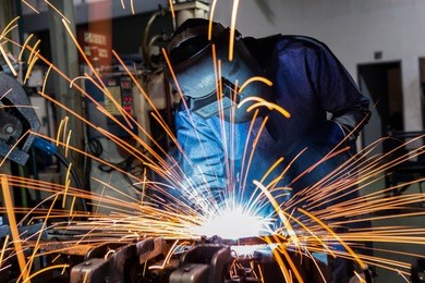 male worker wearing protective clothing welding industrial construction inside confined spaces