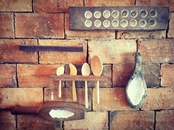 kitchenware made by wood. kitchen utensils hanging on the brick wall.