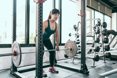 fitness woman deadlift barbell in smith machine in gym. crossfit weightlifting lifestyle.