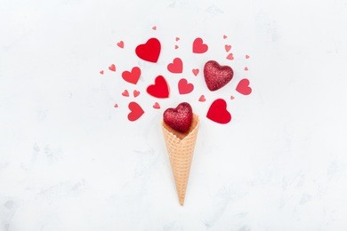 valentines day greeting concept with waffle cone and mixed red hearts on white background top view. fashion flat lay.