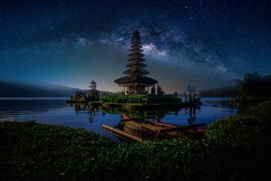pura ulun danu bratan, hindu temple with boat on bratan lake landscape with milky way in bali, indonesia.