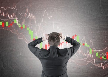 portrait of a blond businessman wearing a suit and pulling out his hair in panic. a rear view. graphs and diagrams drawn on a blackboard