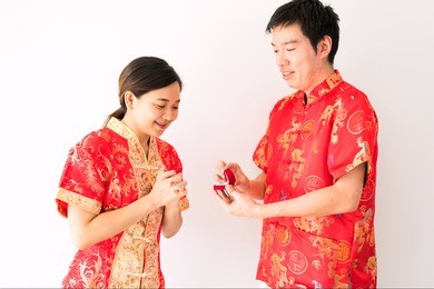 handsome man showing engagement diamond ring to beautiful girlfriend with copy space for text. couple dress red traditional cheongsam costume. 2018 chinese new year with surprise marriage proposal.