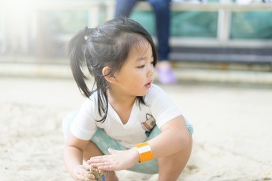 happy kid asian girl playing on white sand beach on the cliff stone beach. cozy vacation on sea.child development.