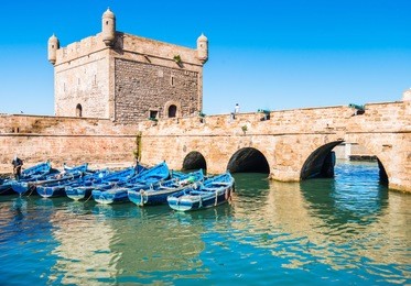 fort of essaouira in morocco on a sunny day with blue boats on the water and selective focus