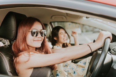 young happy asian girl best friends laughing and smiling in car during a road trip to vacation.