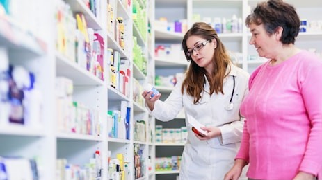 female pharmacist discusses prescription medication with senior customer at pharmacy